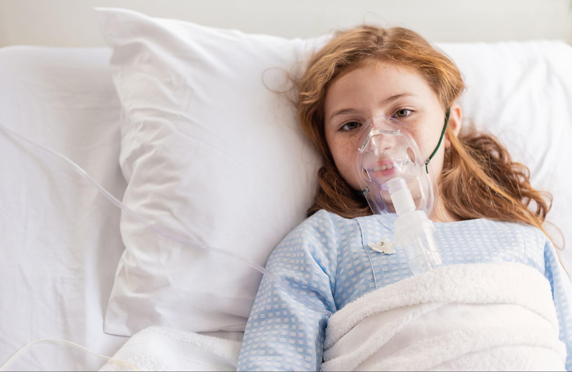 A young patient comfortably resting in bed while using a full face CPAP mask for respiratory support.