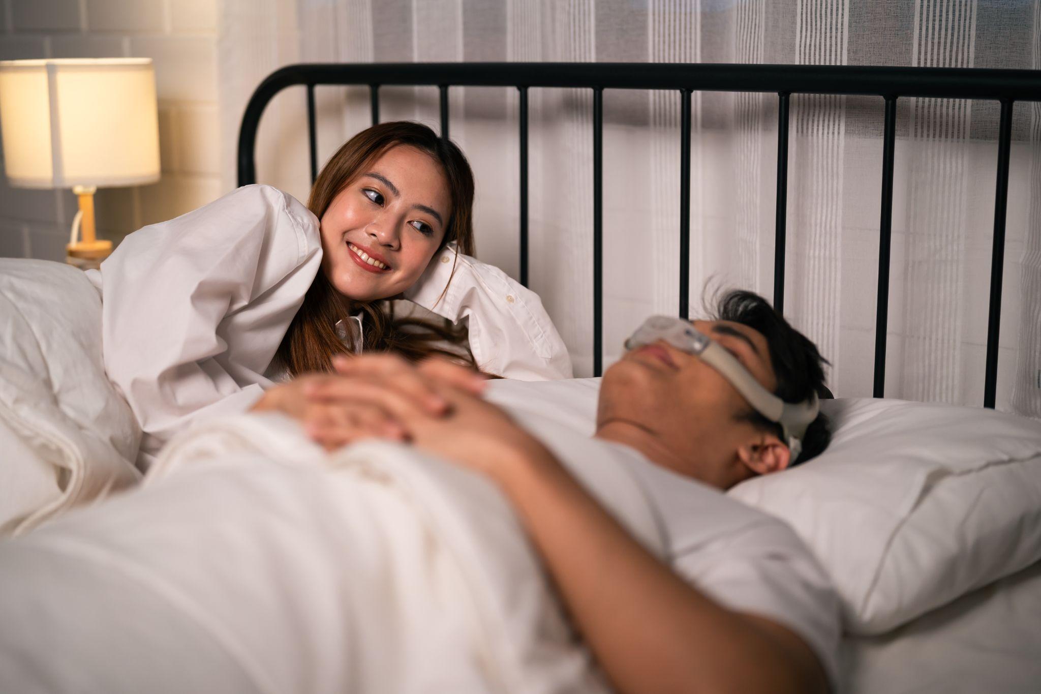 woman looking at husband as he uses CPAP machine