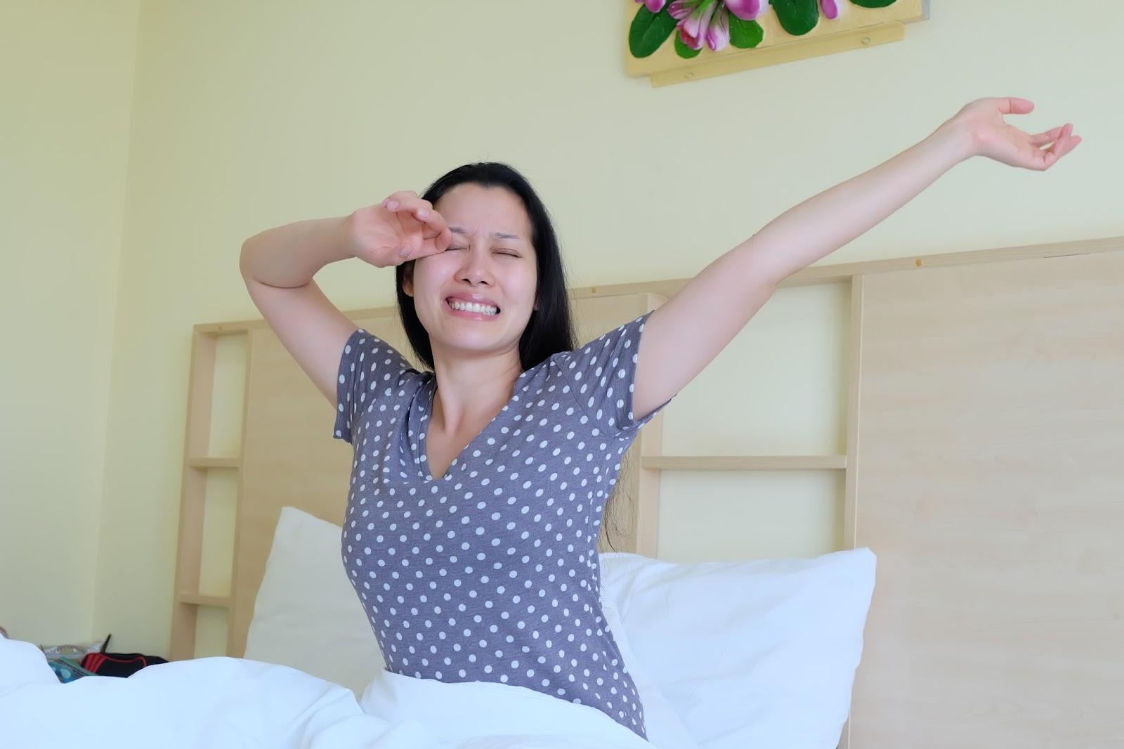 Woman waking up feeling refreshed after a good night’s sleep from consistent CPAP therapy.