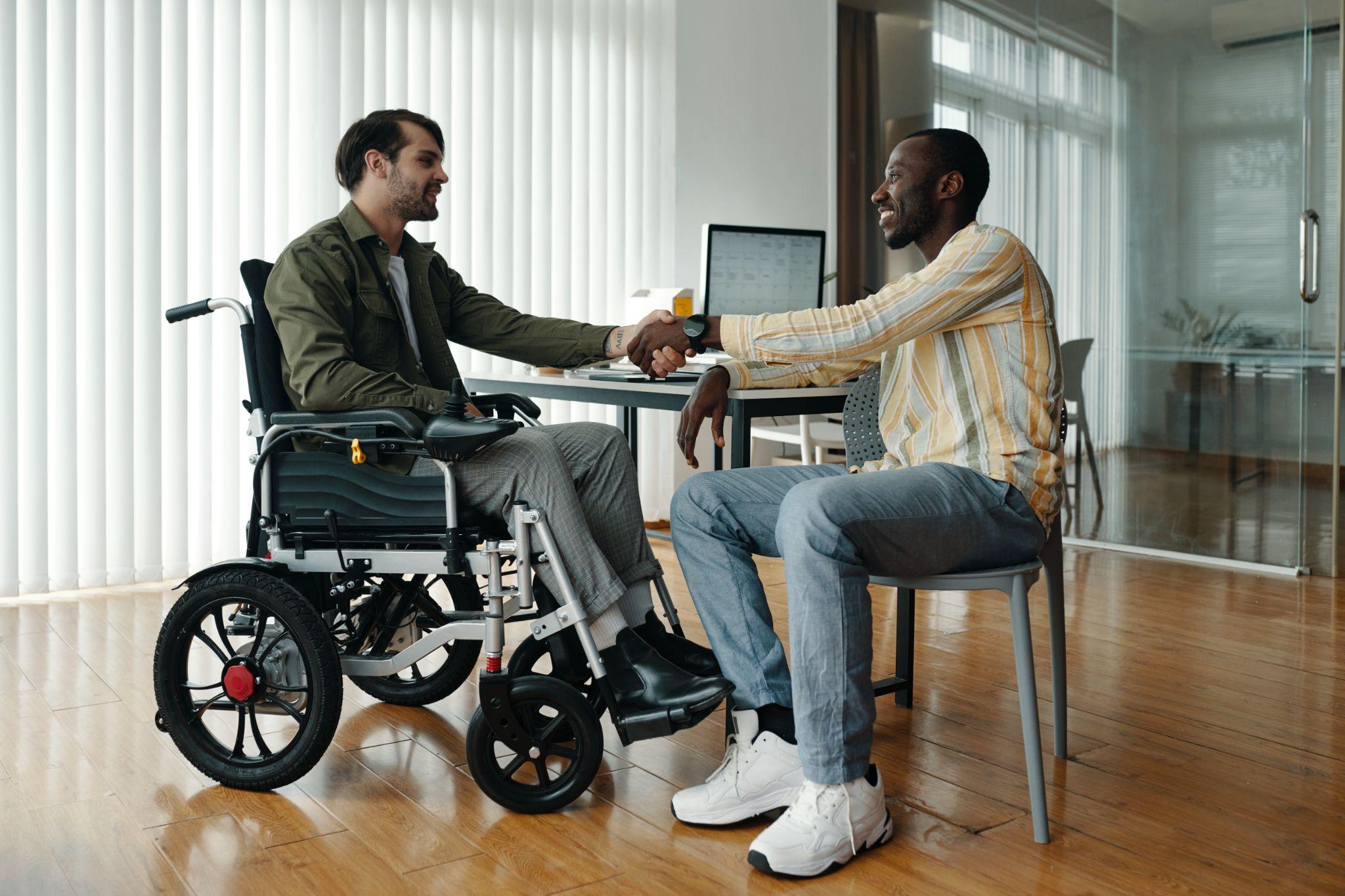 man using wheelchair, talking to colleague