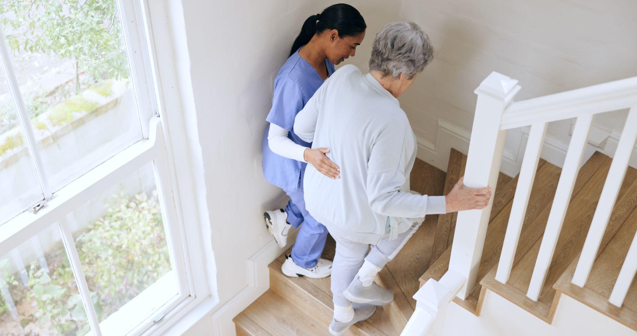 A nurse assisting an elderly person up the stairs.