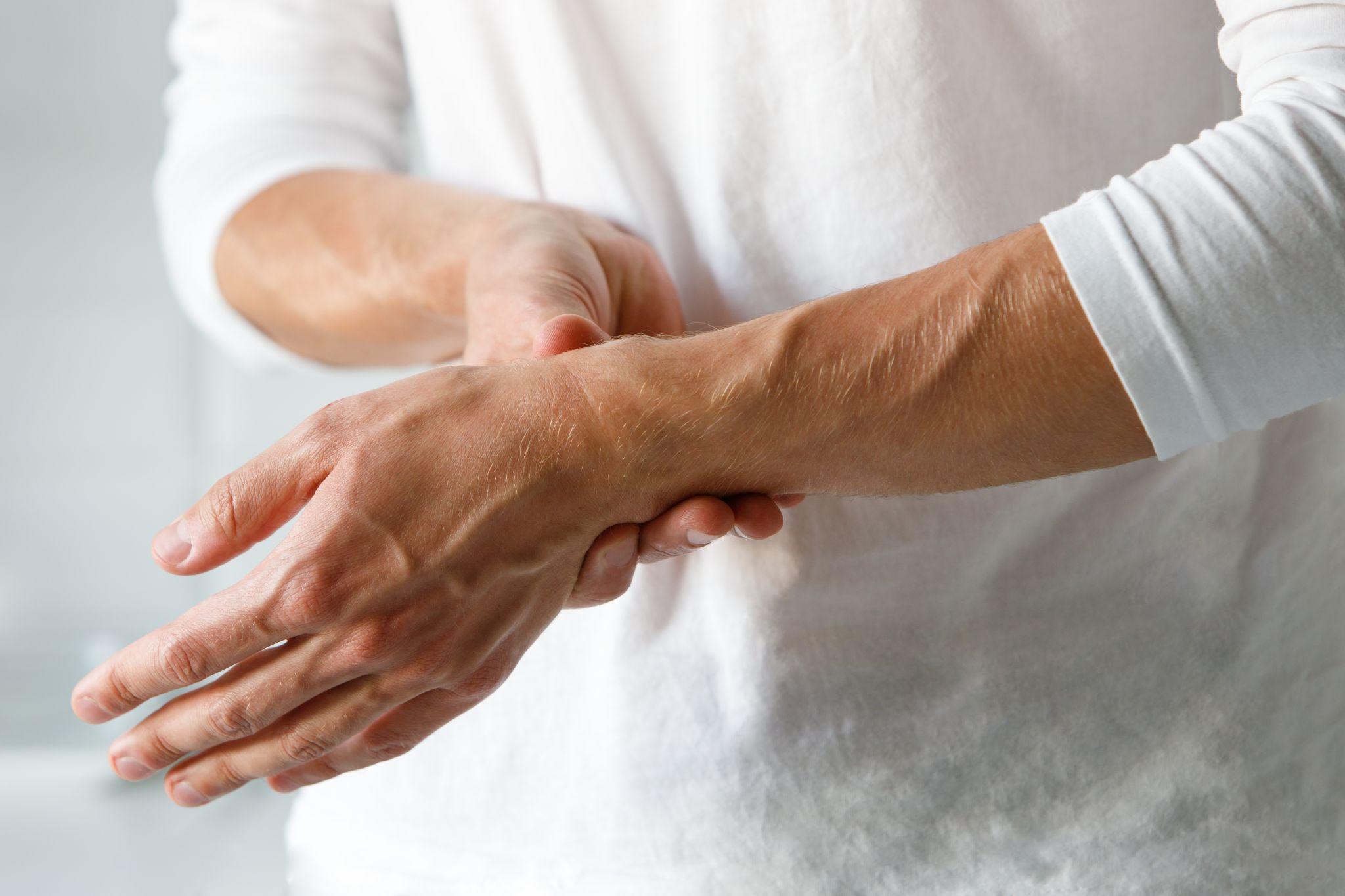 man holding painful wrist, raising the possibility of the need for joint support