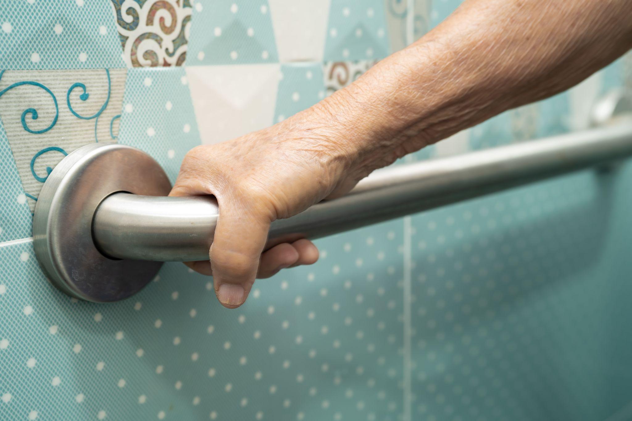 elderly woman using grab bar in bathroom