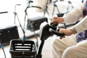 Person adjusting mobility scooter controls in store demonstrating Medicare DME supplier equipment