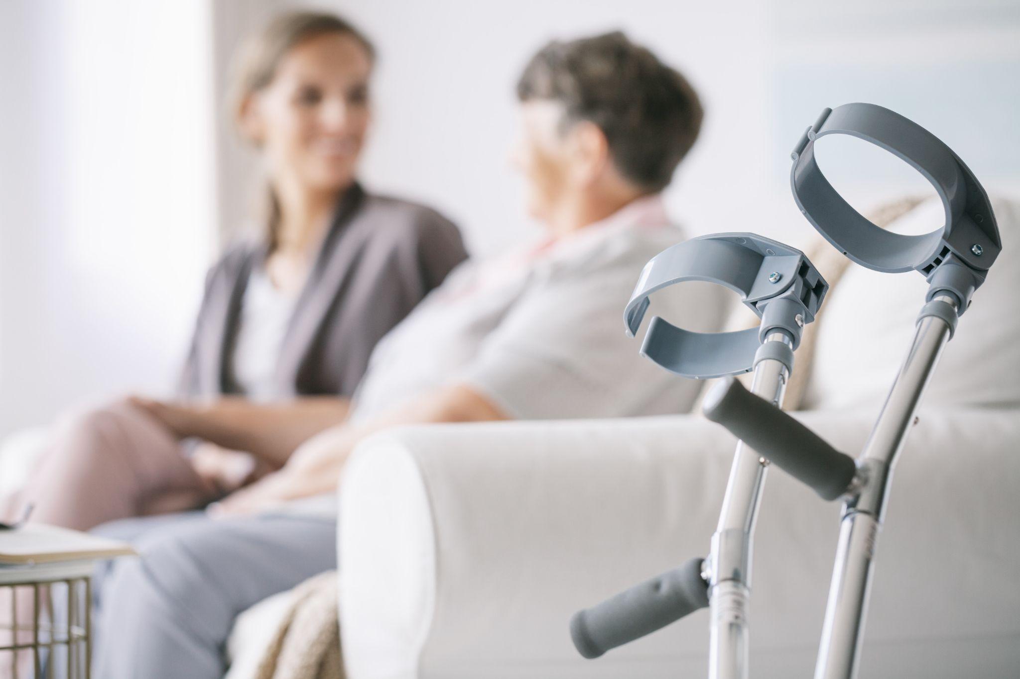 Crutches beside a seated patient during consultation, representing durable medical equipment for injury support