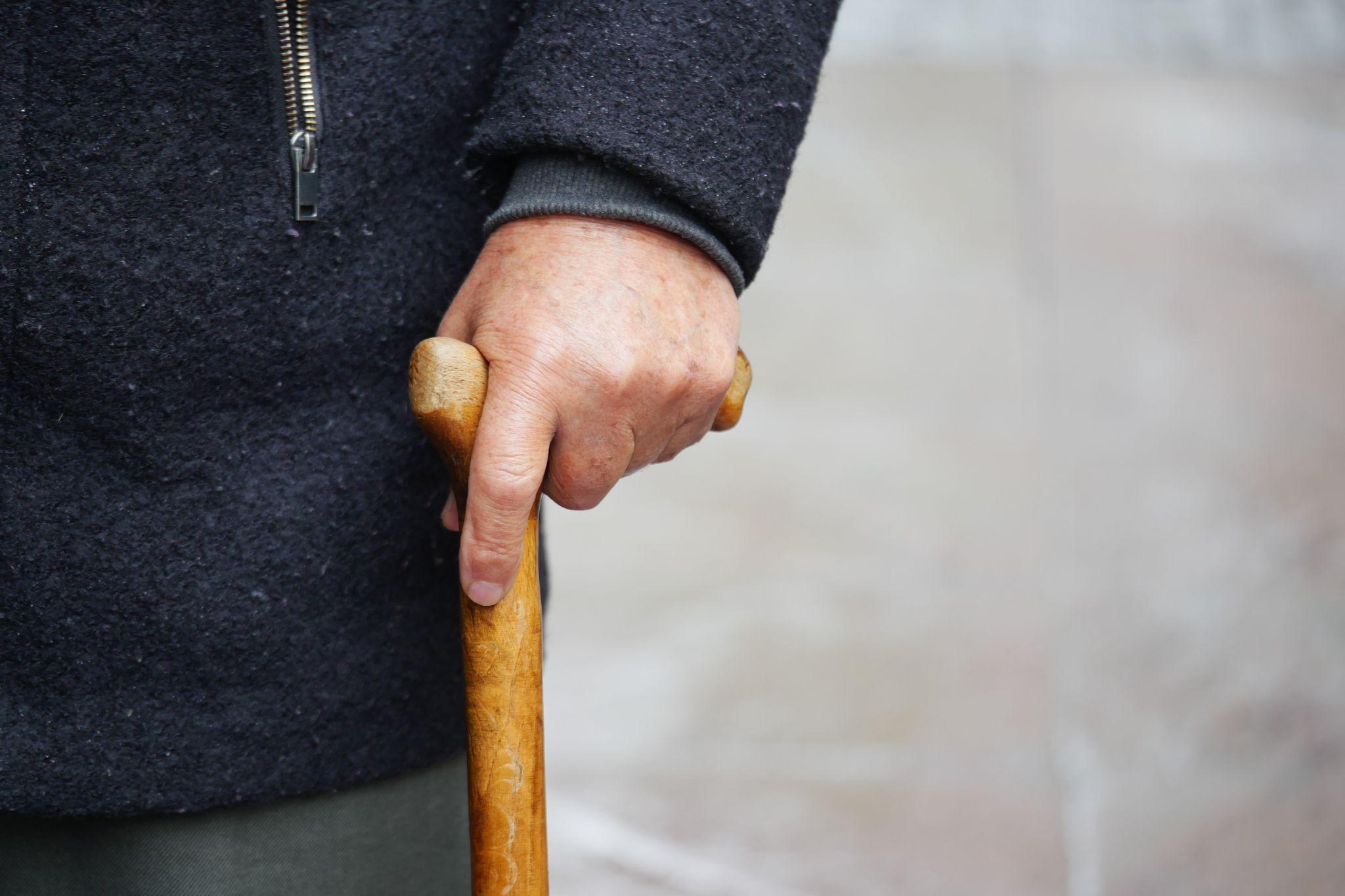 Close-up of an elderly person holding a cane