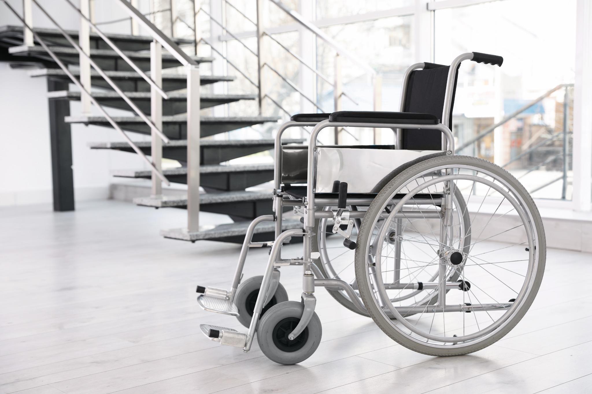 Wheelchair positioned near indoor stairs, highlighting durable medical equipment maintenance for mobility safety and longevity