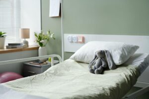 Hospital bed with pillow and stuffed toy showing DME coverage for home medical equipment
