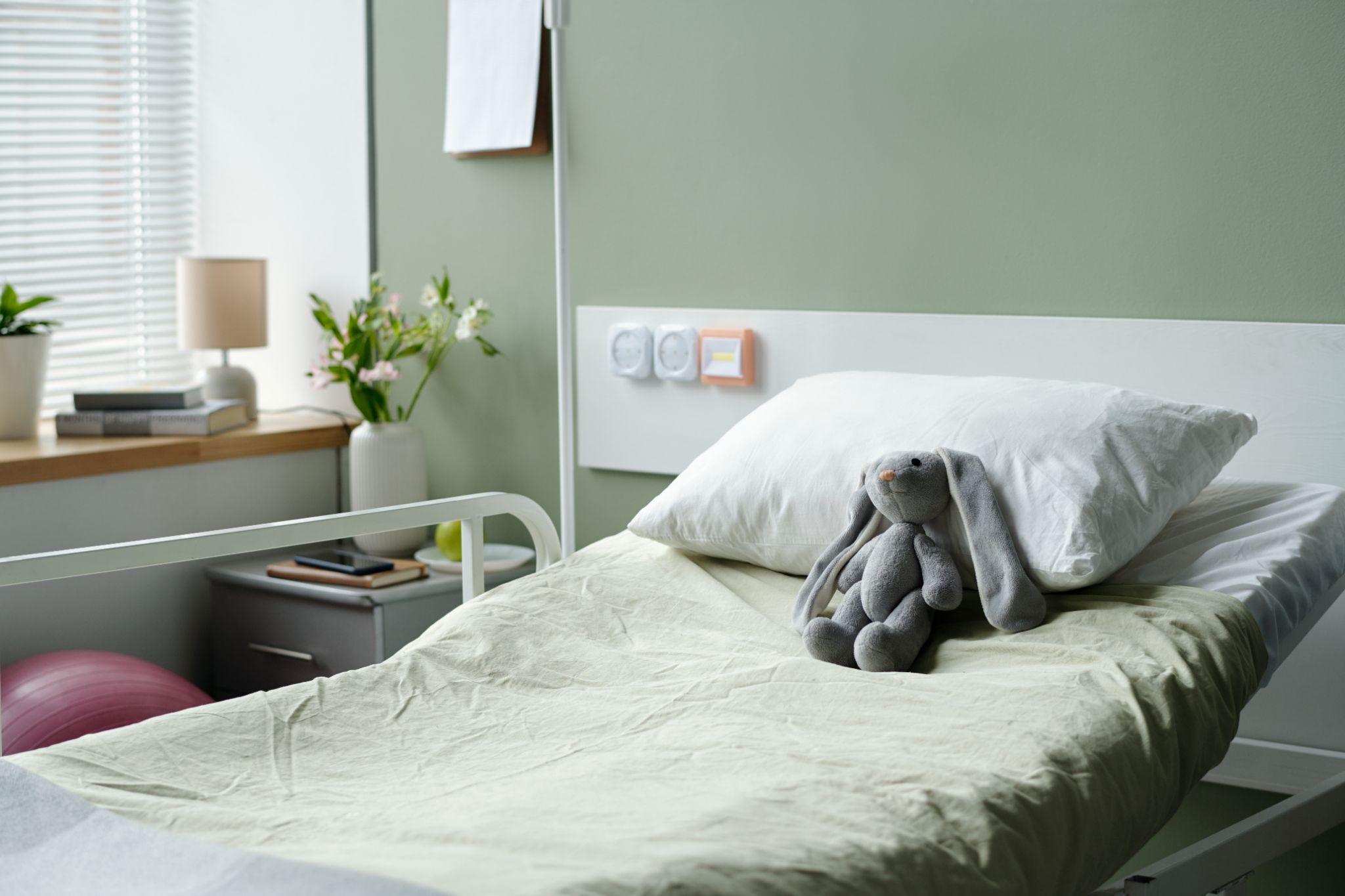 Hospital bed with pillow and stuffed toy showing DME coverage for home medical equipment