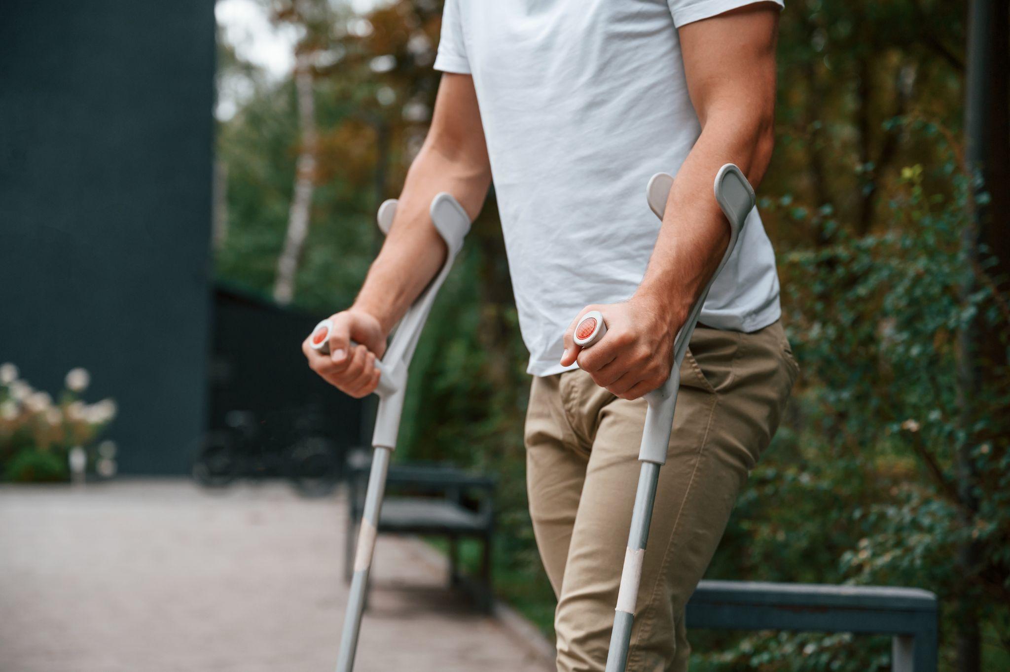 Man using crutches outdoors demonstrating mobility aids under DME coverage