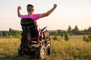 Person in power wheelchair outdoors celebrating mobility with covered medical supplies
