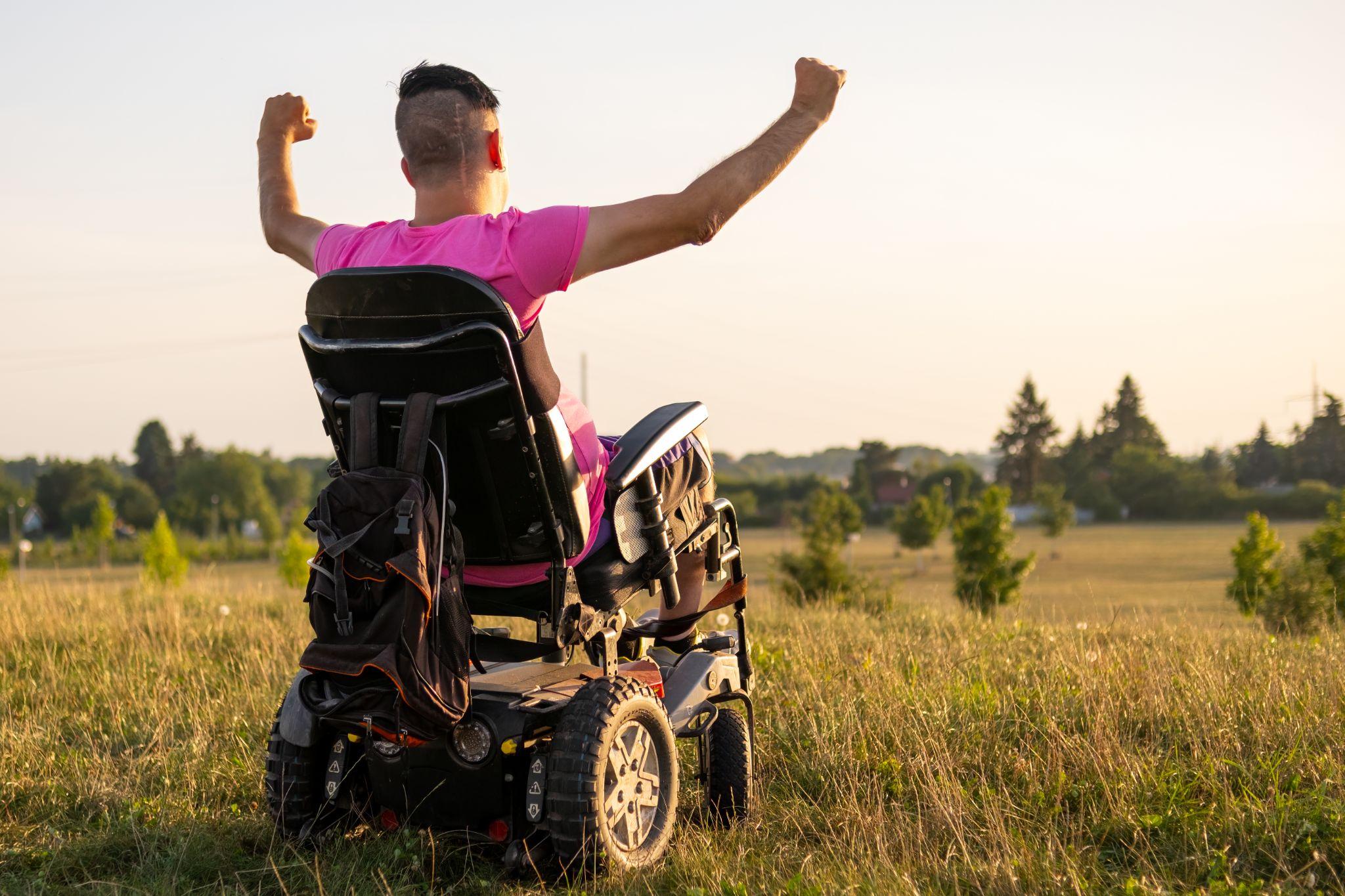 Person in power wheelchair outdoors celebrating mobility with covered medical supplies