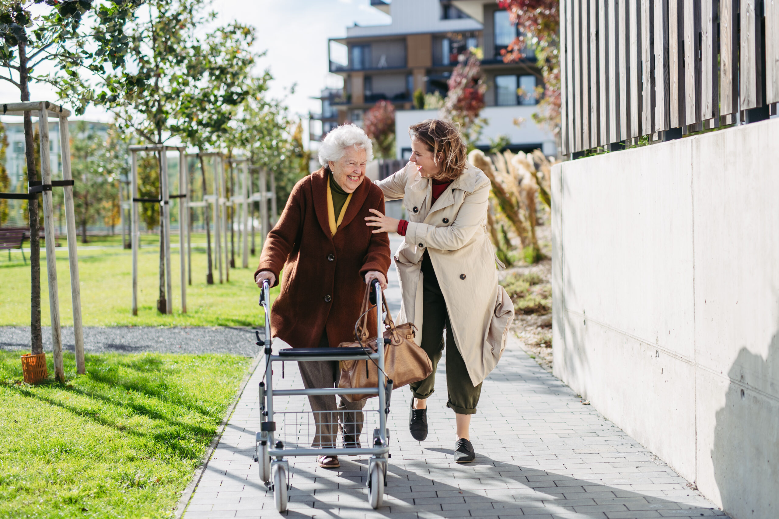 Grandmother and mature granddaughter on a walk in the city park using rollator