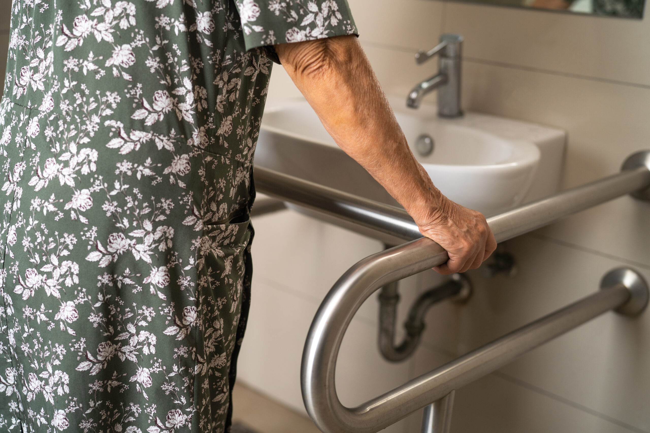 Elderly woman patient using bathroom grab bar