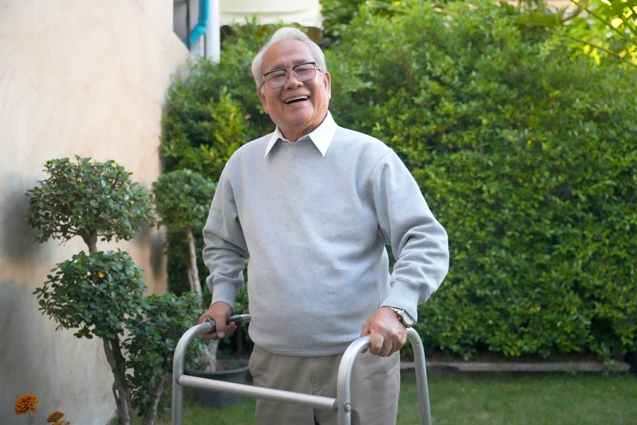 Elderly man uses walker in garden while smiling on a sunny day