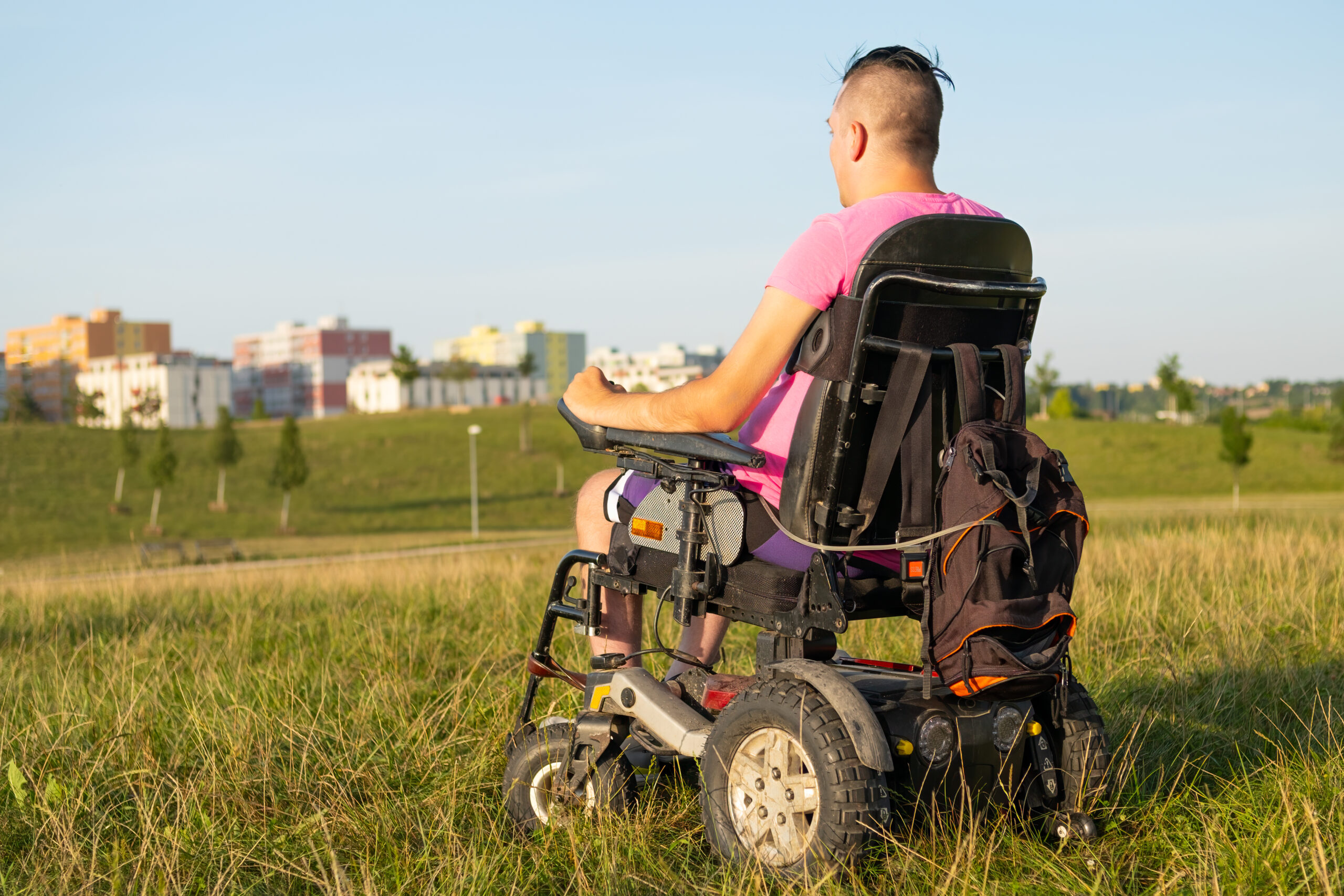 A young man outdoors in a customized power wheelchair, representative of mobility solutions available from a CRT provider in Harlingen.