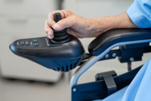 Close-up of a person's hand operating the joystick controller of a power wheelchair
