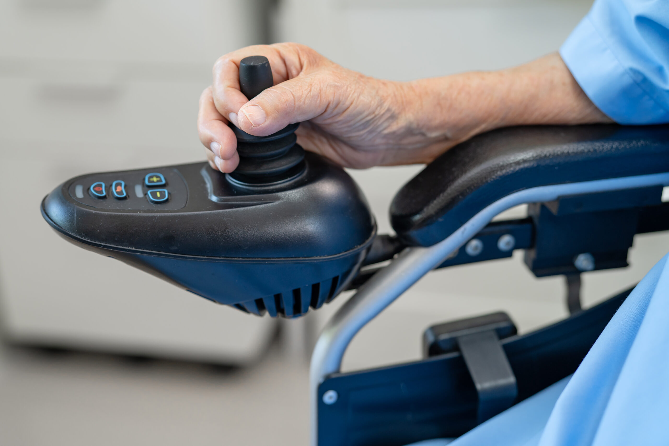 Close-up of a person's hand operating the joystick controller of a power wheelchair