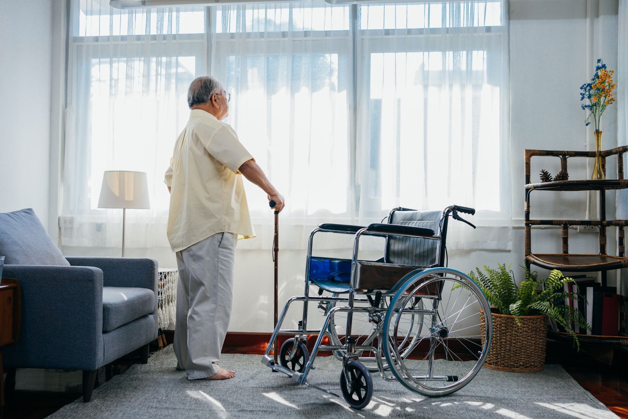 Older adult with a cane and wheelchair in a home setting