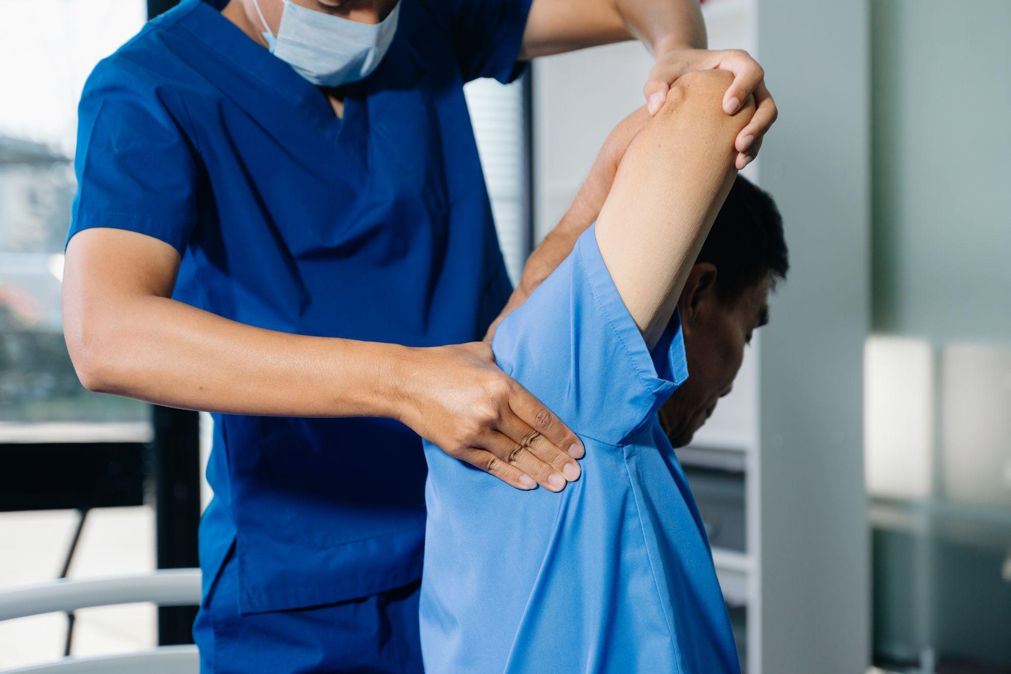Healthcare professional guiding shoulder movement before continued recovery with a shoulder immobilizer.