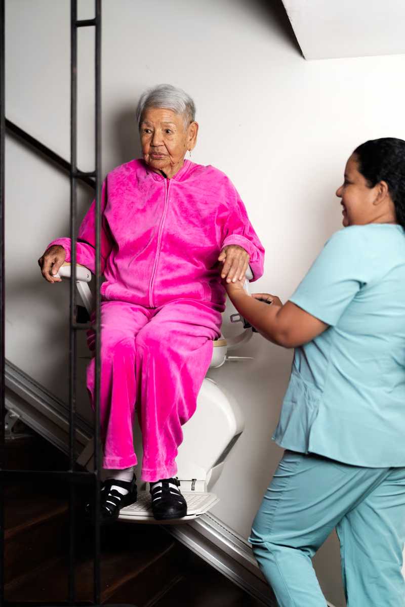 Caregiver assisting an older adult using a patient lift for safer mobility and transfers at home.