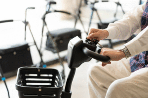 Person testing scooter controls for a Harlingen mobility scooter rental, with mobility equipment displayed in the background.
