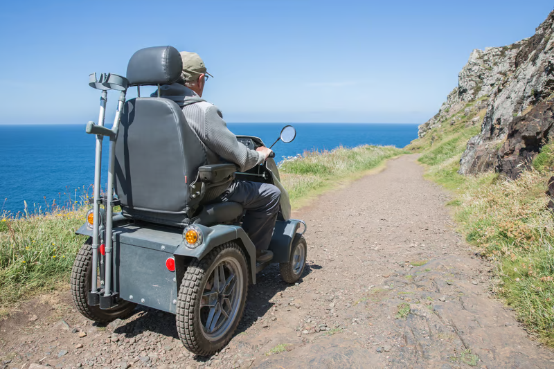 Person riding a heavy-duty mobility scooter on an outdoor trail, showing an option to consider for a Harlingen mobility scooter rental.