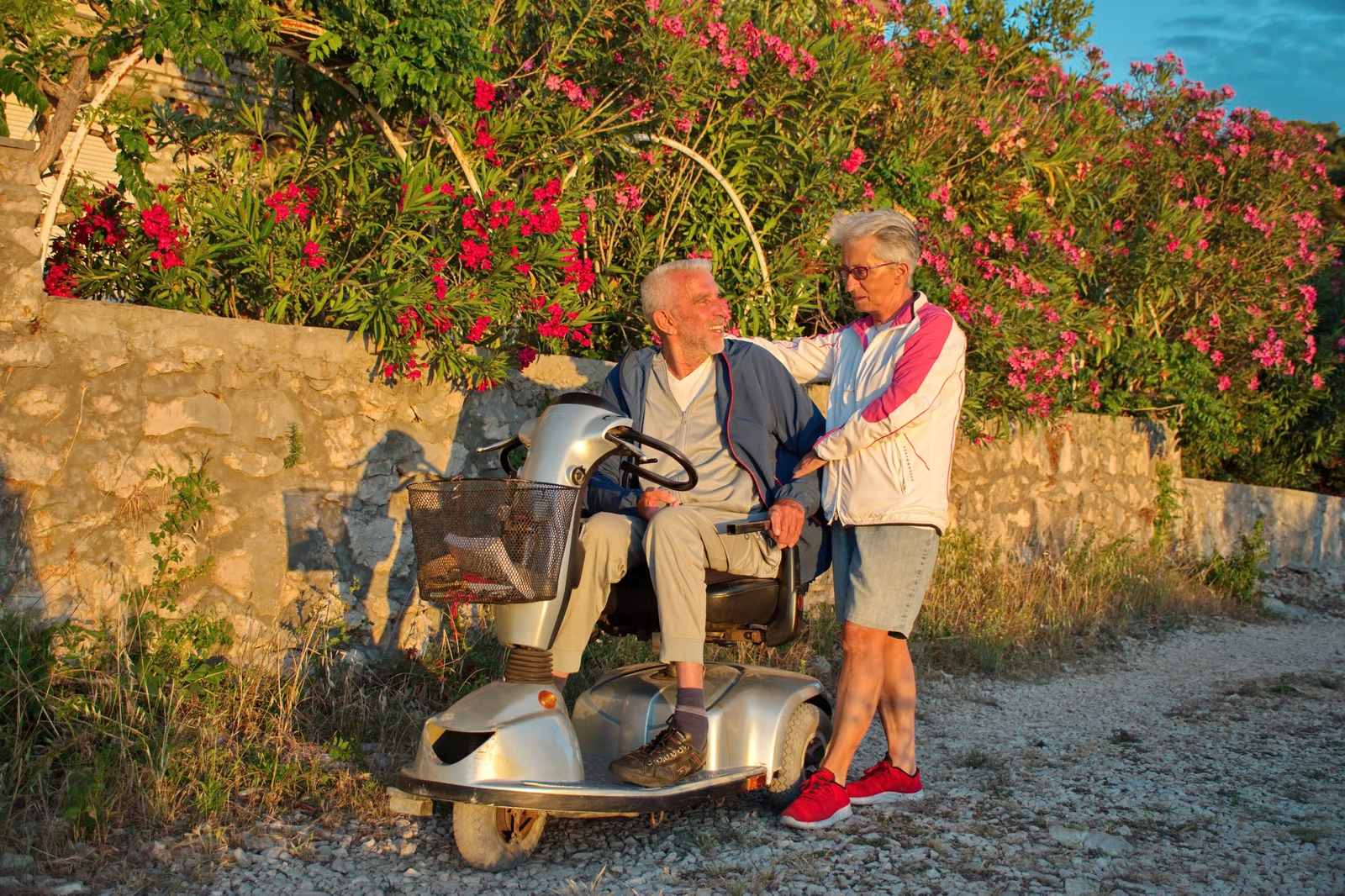Older adult using a mobility scooter outdoors with a companion, showing the independence a Harlingen mobility scooter rental can provide.