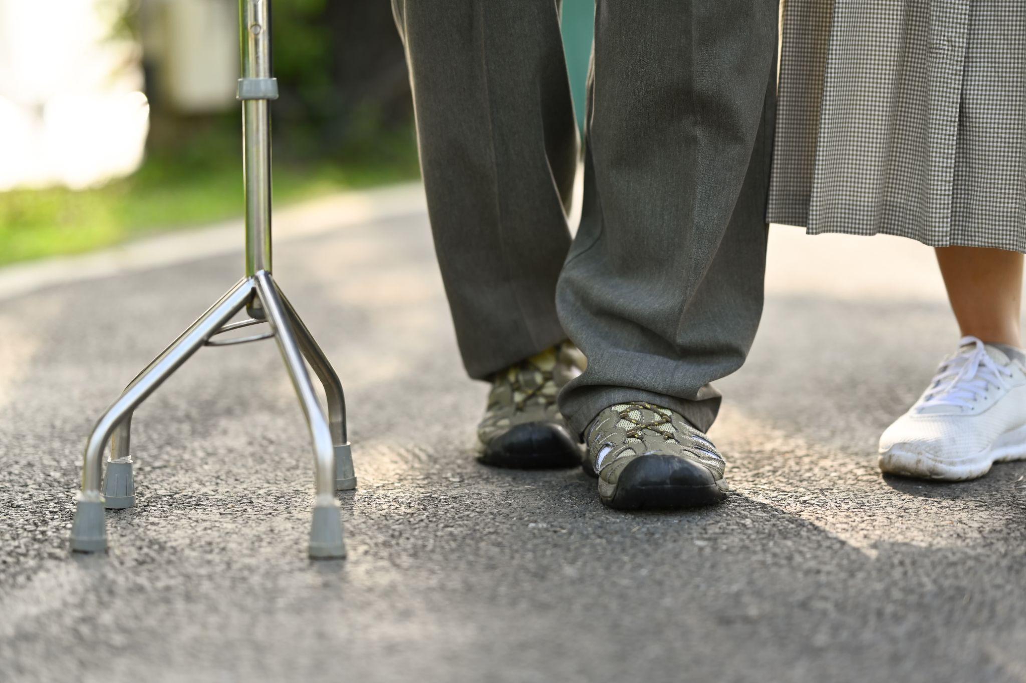 Older adult walking outdoors with mobility support