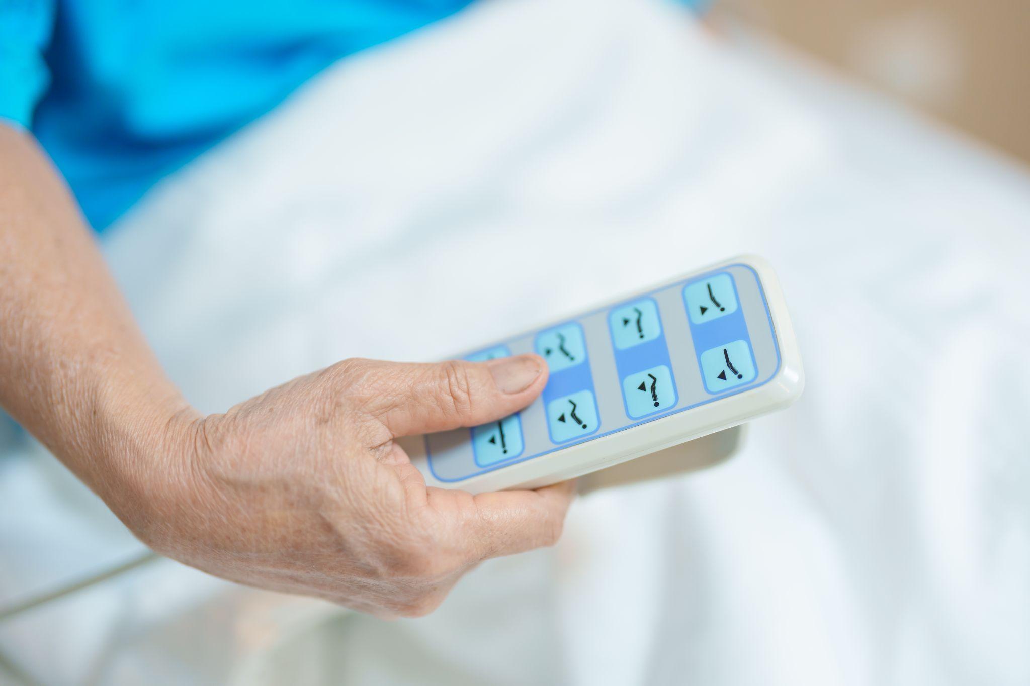 Hand using a hospital bed remote control to adjust bed positioning