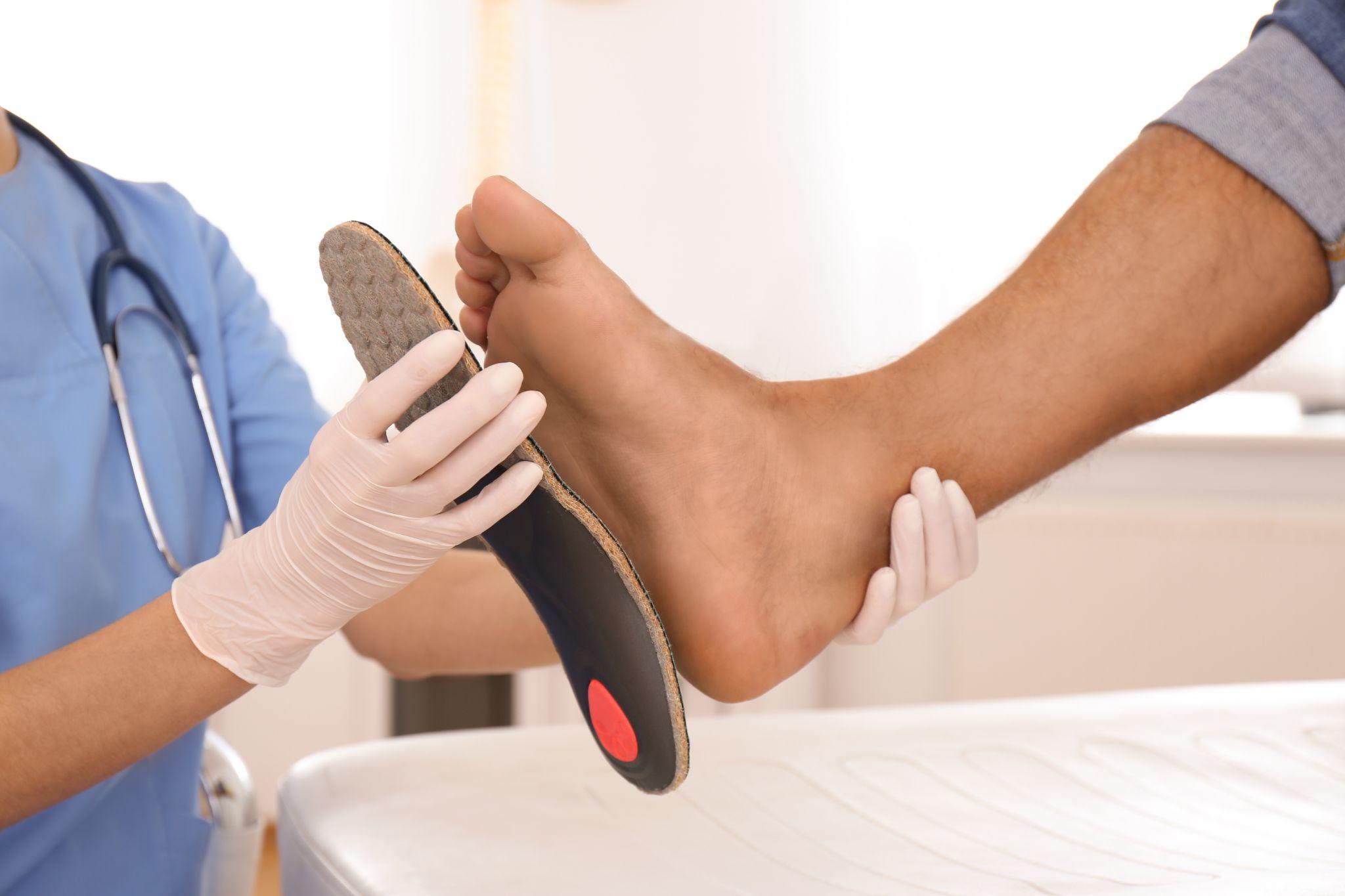 Healthcare professional fitting an orthotic insole to a patient’s foot