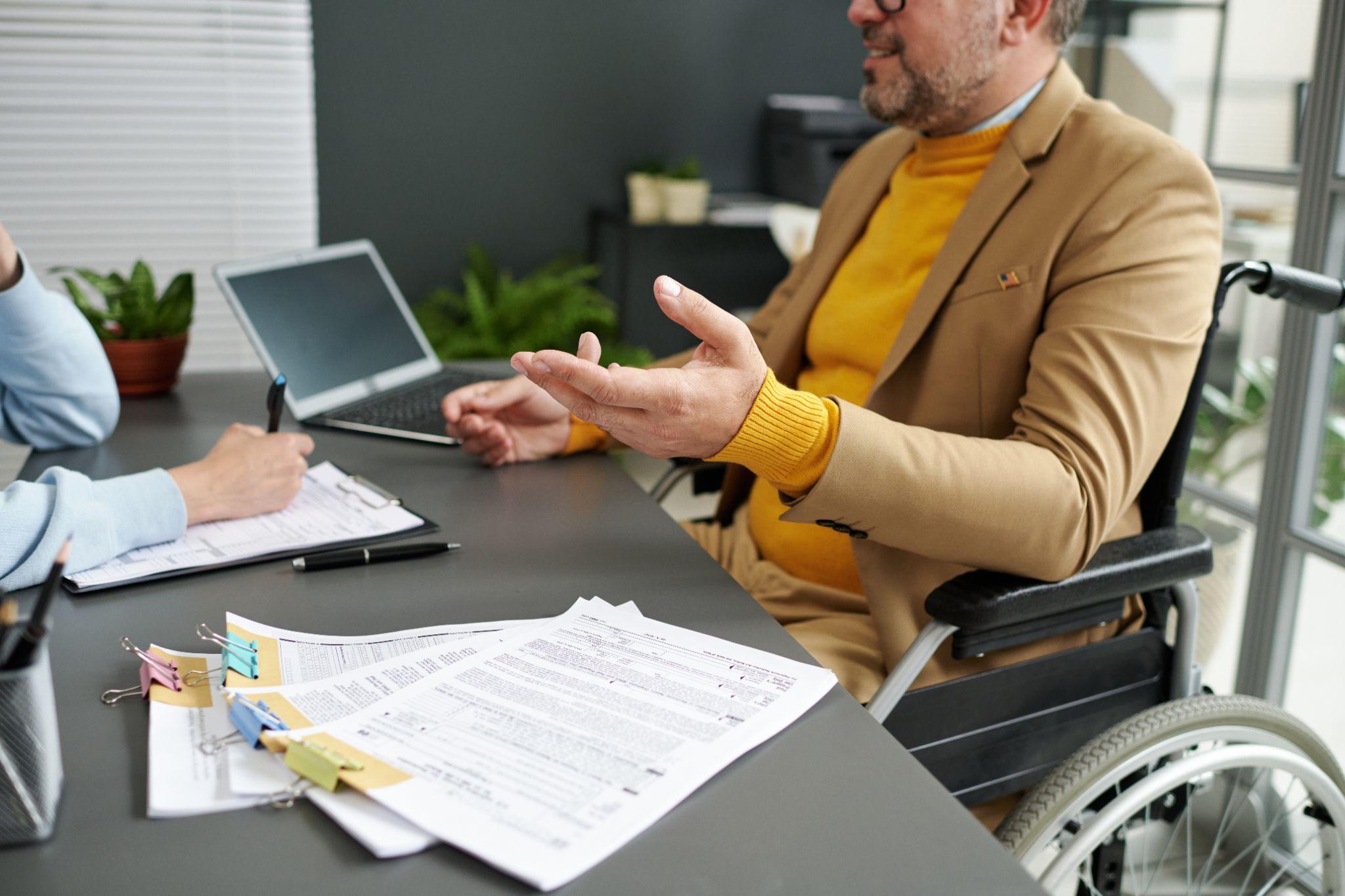 Wheelchair user reviewing medical and insurance paperwork with a professional