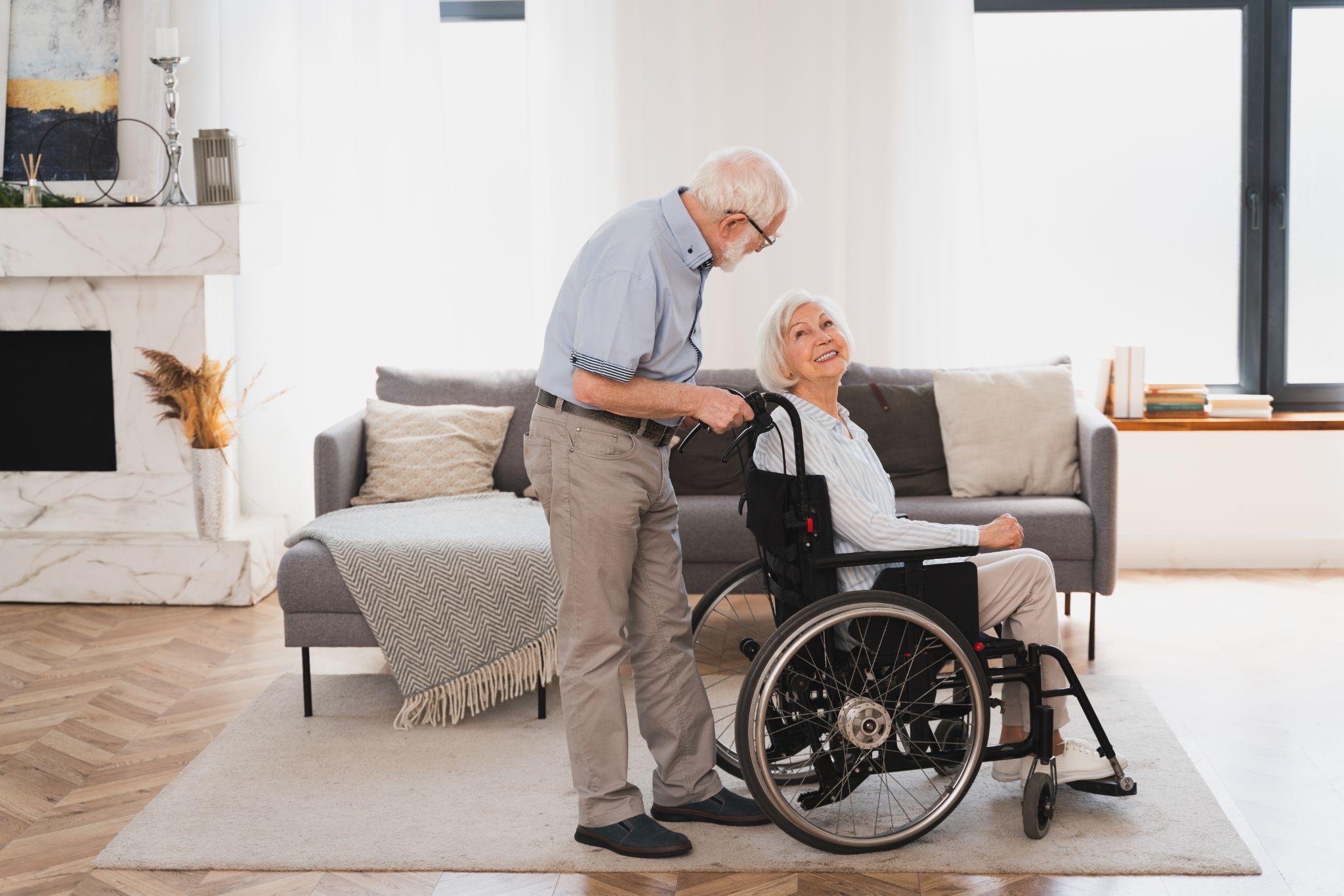 Senior woman using a wheelchair safely at home with caregiver assistance