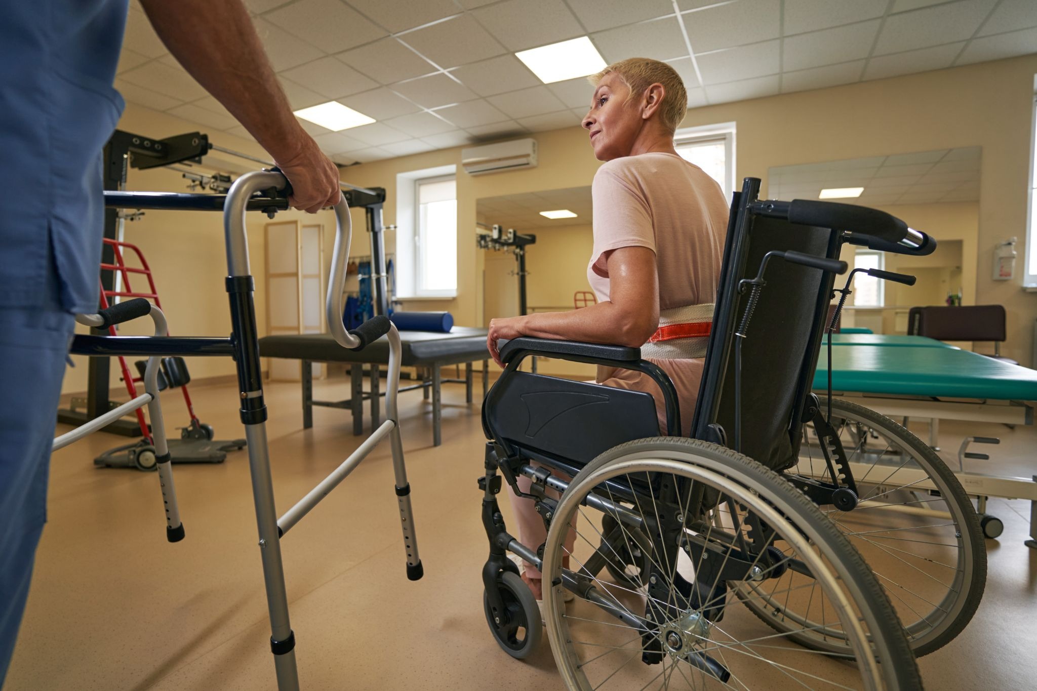 Therapist helping a wheelchair user with walker fitting and mobility support