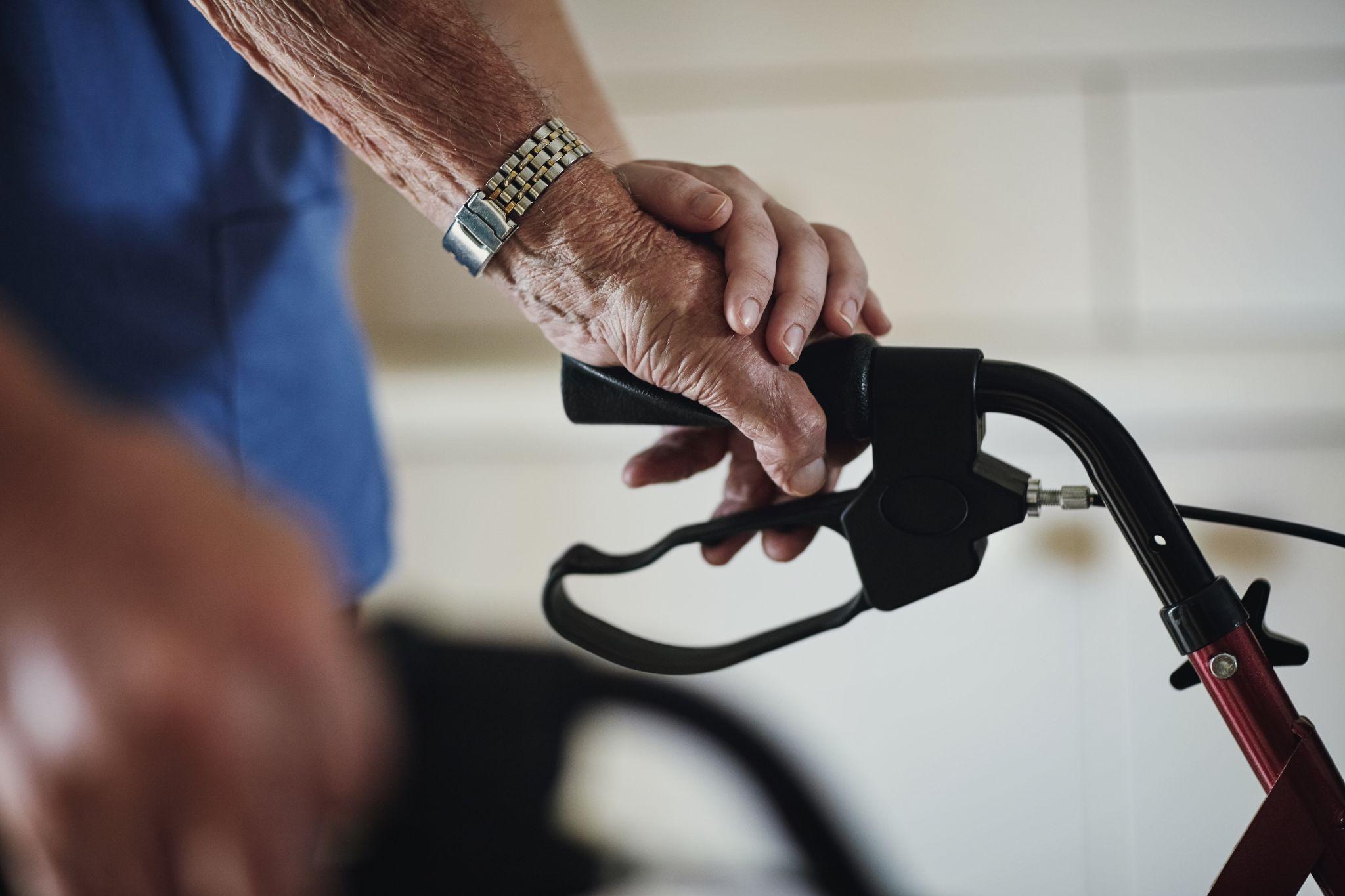 Healthcare professional assessing an older adult's mobility while using a walker.