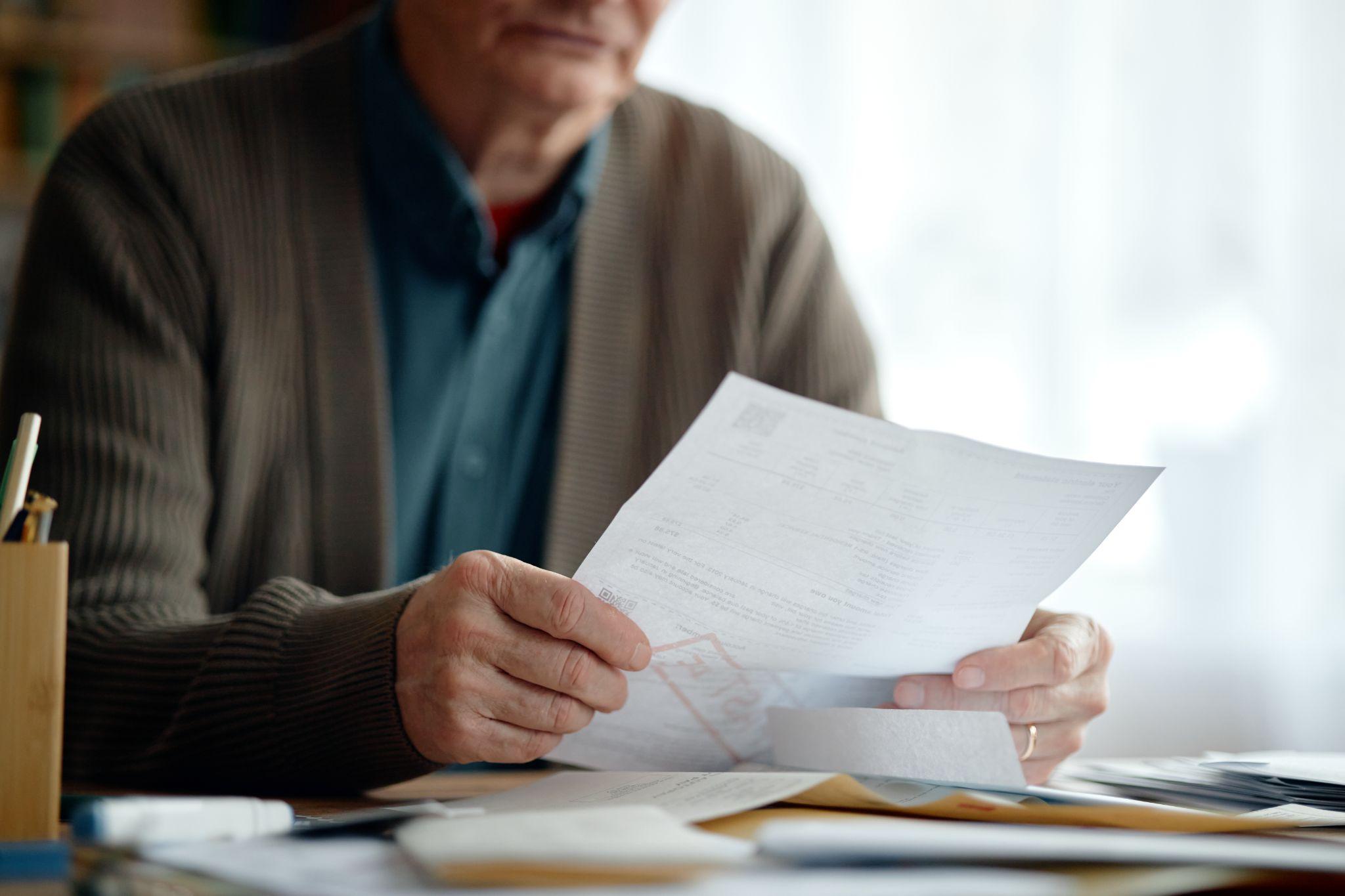Senior man reviewing billing documents while managing medical expenses and insurance concerns.
