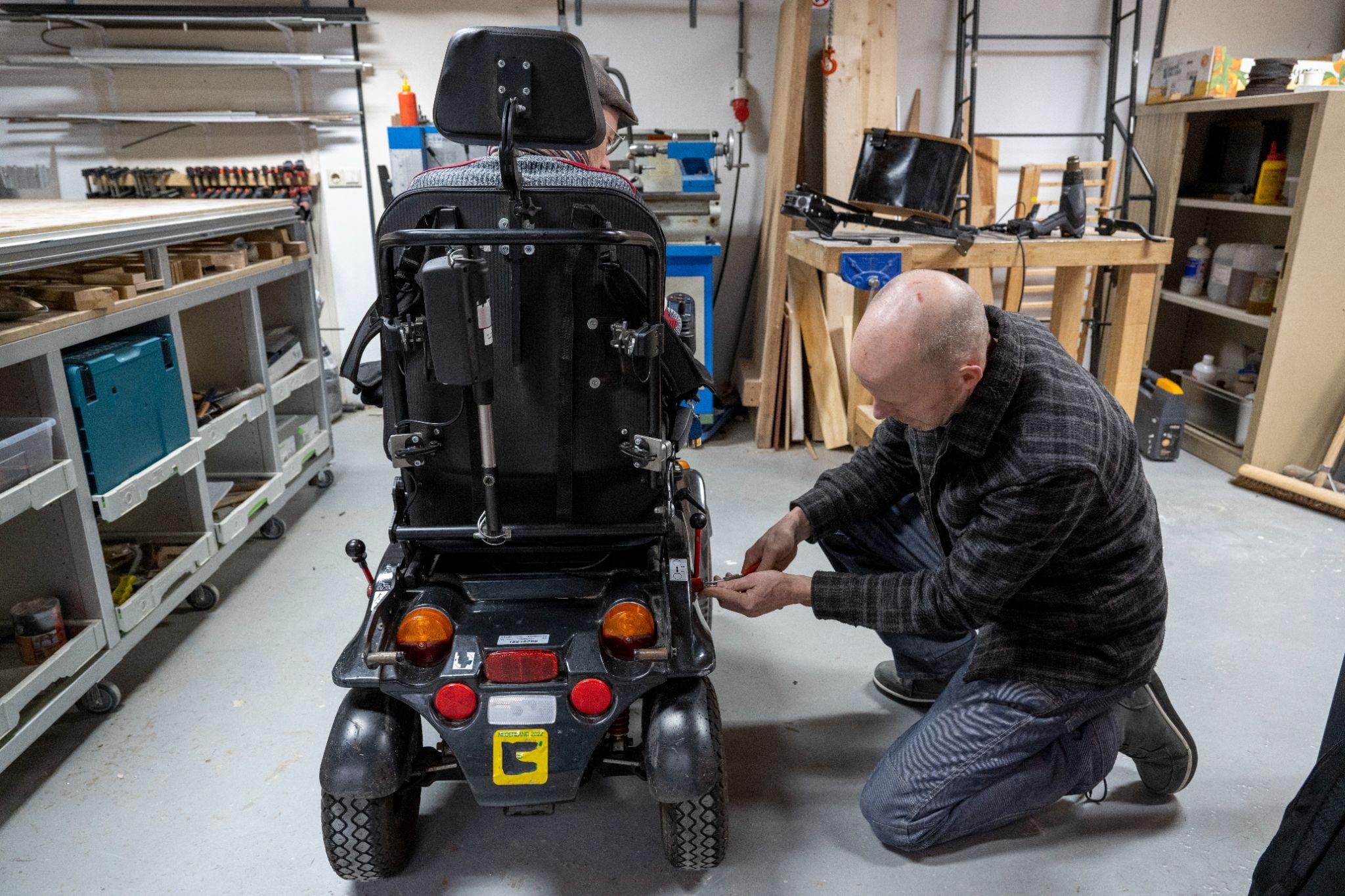 Technician repairing mobility equipment in a workshop to support ongoing equipment maintenance.